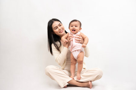 Beautiful mother and adorable baby girl are happy on white background, family, child, childhood and parenthood conceptの写真素材