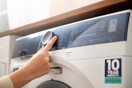 Close-up woman hand pushing washing machine buttons for setting program or start laundry  , health care lifestyle conceptの写真素材