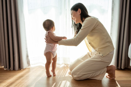 A baby girl learning first steps walk with mother, family, child, childhood and parenthood concept