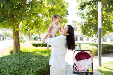 A Beautiful mom holding a baby girl in her arms outdoor in sunshine day