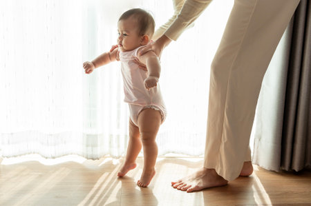 A baby girl learning first steps walk with mother, family, child, childhood and parenthood conceptの写真素材