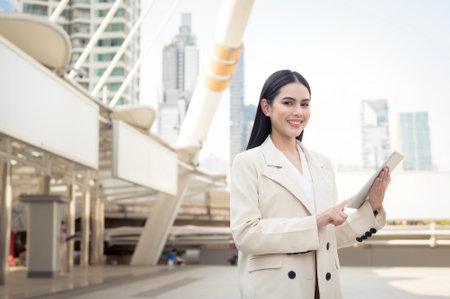 Portrait of young beautiful businesswoman using tablet in modern cityの写真素材