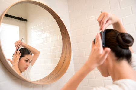 Young woman adjusting her hairstyles in bathroom at home , beauty wellness conceptの写真素材