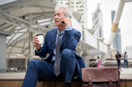 Asian senior mature middle aged businessman using smartphone in modern cityの写真素材