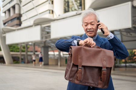 Asian senior mature middle aged businessman using smartphone in modern city