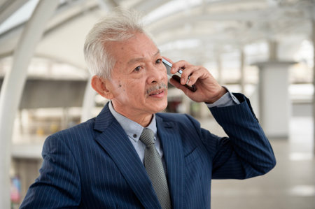 Asian senior mature middle aged businessman using smartphone in modern city