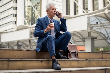 Asian senior mature middle aged businessman using smartphone in modern cityの写真素材