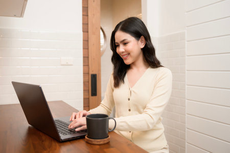 An Asian young woman using laptop computer online working at home , lifestyle and teleworking conceptの写真素材