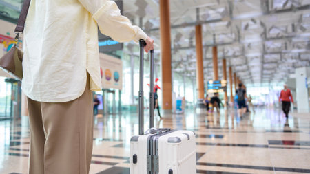 Close-up woman hand walking with suitcase , check in at International airport , vacation travel and transportation conceptの写真素材