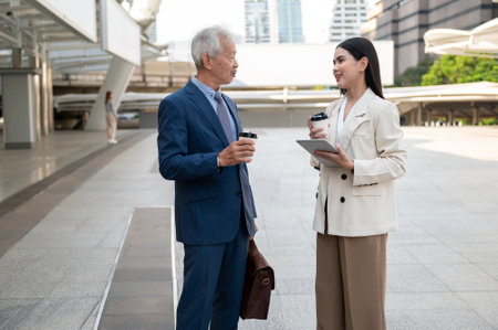 Asian senior mature middle aged businessman and young businesswoman having a discussion and coffee in modern cityの写真素材