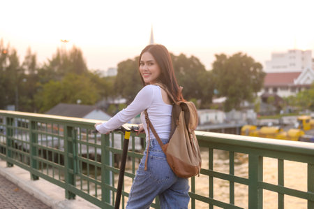 Portrait of young beautiful woman with an electric scooter  over bridge in modern city  backgroundの写真素材