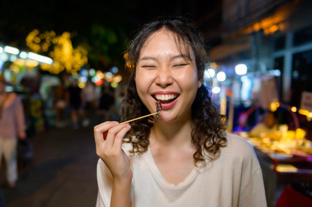 Beautiful young Asian tourist woman on vacation sightseeing and exploring at Khao San road at night in Bangkok city, Thailand, Holidays and traveling conceptの写真素材