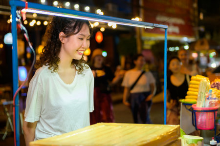 Beautiful young Asian tourist woman on vacation sightseeing and exploring at Khao San road at night in Bangkok city, Thailand, Holidays and traveling conceptの写真素材