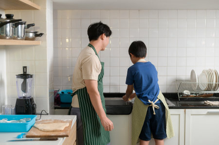 Happy smiling Young Asian father and son washing dishes in kitchen at homeの写真素材