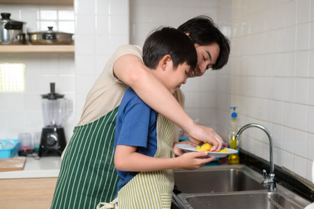 Happy smiling Young Asian father and son washing dishes in kitchen at homeの写真素材