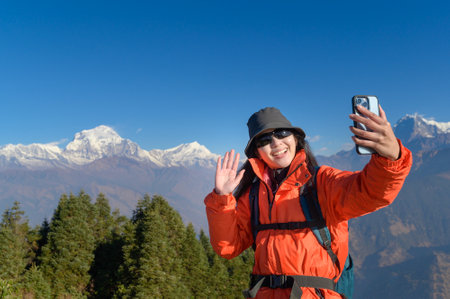 A young traveler takes a selfie or a video call while standing a top a mountain.の写真素材