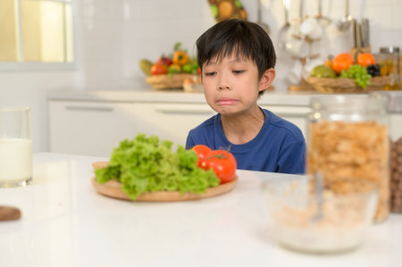 Asian boy feeling bored , unhappy to eat vegetables , health care conceptの写真素材