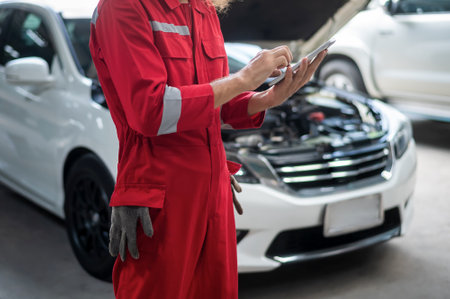 Close-up technician man hand using tablet analyzing car problems in auto repair shop . concept of auto repair and maintenance service.の写真素材