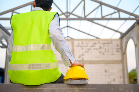 Engineering man with safety helmet siting over construction site background analyzing about project progressの写真素材