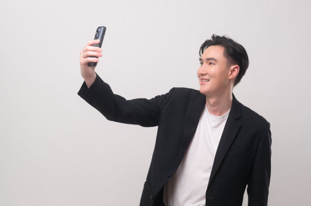 Asian Young businessman wearing  suit using smartphone  over white background studioの写真素材