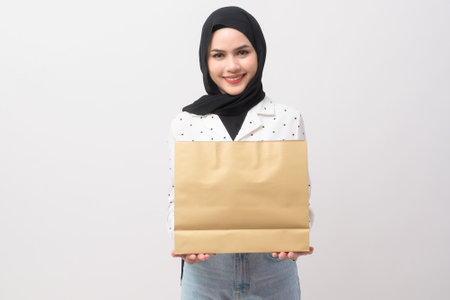 Beautiful musllim woman with hijab holding credit card and shopping bag over white background studio, shopping and finance concept.の写真素材
