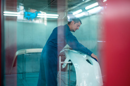 Caucasian man is cleaning car parts before spraying color in repair mechanic painting shop