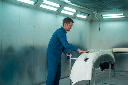 Caucasian man is cleaning car parts before spraying color in repair mechanic painting shopの写真素材