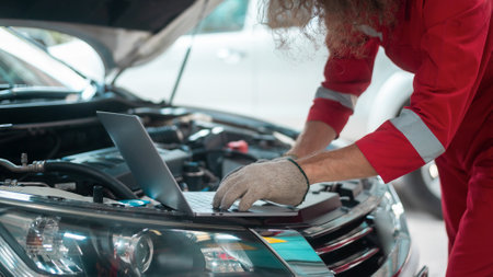 Young caucasian repairman analyzing and fixing broken car in car repair mechanic shopの写真素材