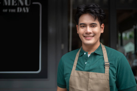 Young Asian man cafe owner entrepreneur smiling in coffee shop, small business conceptの写真素材