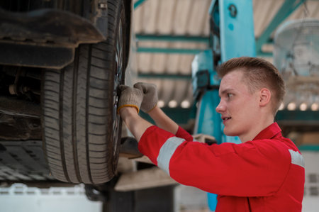 Young caucasian repairman analyzing and fixing broken car in car repair mechanic shopの写真素材