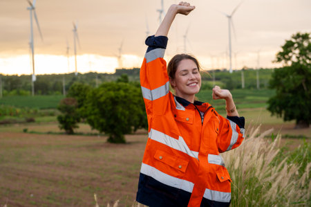 Smart engineer with protective helmet rising hands up  at electrical turbines fieldの写真素材