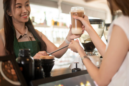 Young Asian service minded barista  with customer in coffee shopの写真素材