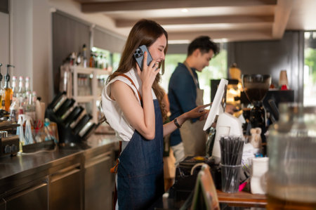 Young Asian service minded barista  with customer in coffee shopの写真素材