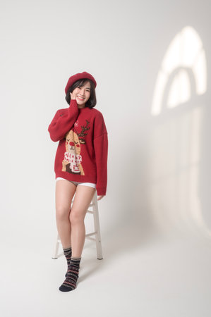 Young happy woman in santa claus hat wearing red sweater over white background, Christmas conceptの写真素材