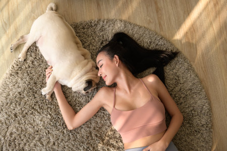 Happy young asian woman cuddling and spending time with cute dog in living room.の写真素材
