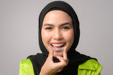Muslim woman with hijab holding invisalign braces in studioの写真素材