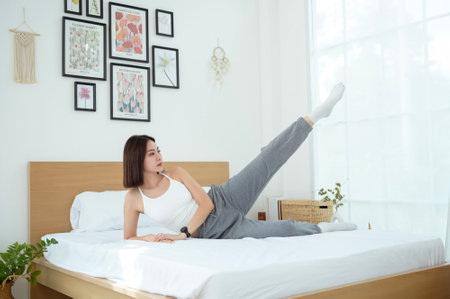 Young Asian woman doing exercise workout in bedroom at homeの写真素材