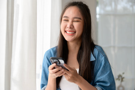 Young Asian woman enjoy using smartphone at homeの写真素材