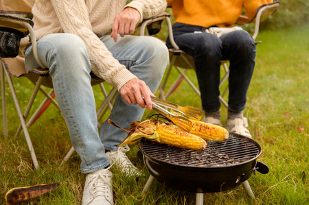 Couple Grilling food on a portable barbeque while relaxing in a garden on a warm afternoon.の写真素材