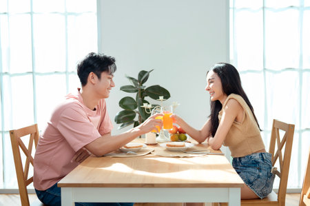 A young couple shares a light-hearted breakfast, surrounded by warm sunlight and decorations.の写真素材
