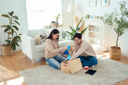 A couple joyfully holds indoor plants and wicker baskets in a bright, airy living space.の写真素材