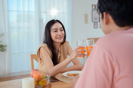 A young couple shares a light-hearted breakfast, surrounded by warm sunlight and decorations.の写真素材
