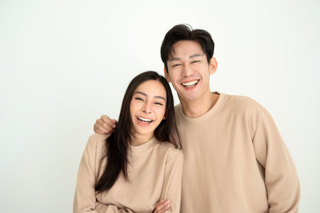 A young couple poses with smiles, dressed in beige tops, exuding happiness.の写真素材