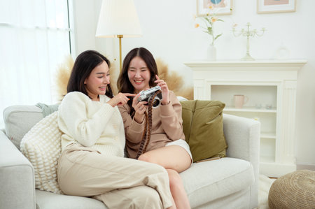 Two young Asian woman friends using camera in living room  at homeの写真素材