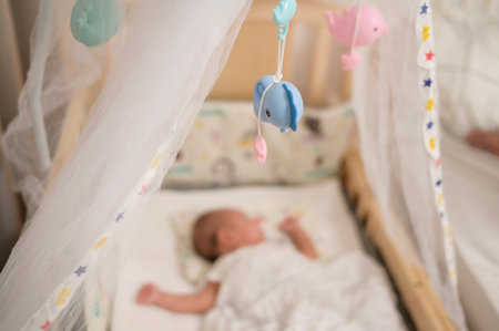 A baby is resting soundly on a soft blanket in a comfortable crib filled with toys.の写真素材