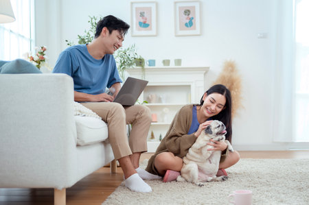 A young couple relaxes on a sofa with their dog, sharing joyful moments in a bright living space.の写真素材