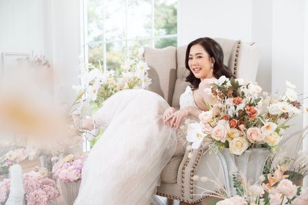 A bride in a stunning gown enjoys a moment among exquisite floral displays in a bright room.の写真素材