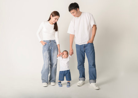 A happy family of three enjoys a playful moment in a studio setting, showcasing their love.の写真素材