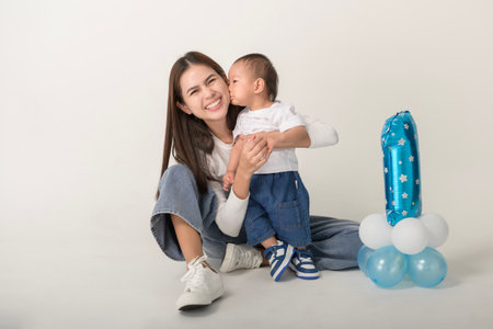 A joyful mother celebrates her child's first birthday while holding her son in a happy pose.の写真素材