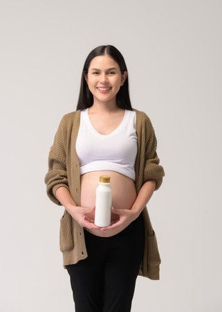 Pregnant woman drinking milk over white background studio
